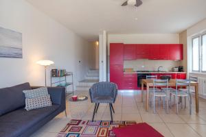 een woonkamer met een bank en een keuken met rode kasten bij Villa Tremezzo in Tremezzo
