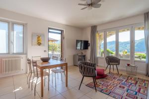 a dining room with a table and chairs and windows at Villa Tremezzo in Tremezzo