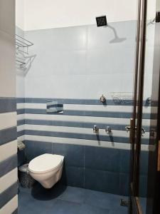 a bathroom with a toilet and blue and white stripes at Saaketh Holiday Home(2) in Kozhikode +12 photos