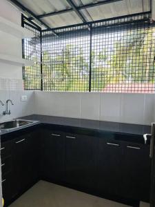 eine Küche mit schwarzen Schränken, einem Waschbecken und einem Fenster in der Unterkunft Saaketh Holiday Home(2) in Kozhikode + 12 Fotos