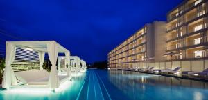 a hotel with a swimming pool at night at Hoshino Resorts BEB5 Okinawa Serakaki in Onna