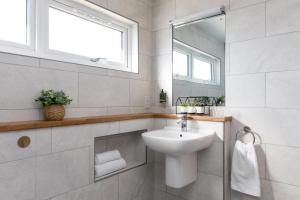 a white bathroom with a sink and a mirror at The Stables in Chichester +19 photos
