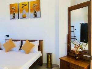 1 dormitorio con cama con almohadas amarillas y espejo en Kavin beach hotel en Hikkaduwa