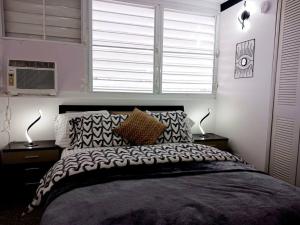 ein Schlafzimmer mit einem Bett mit zwei Lampen und einem Fenster in der Unterkunft Elegancia Acogedora: Tu Rincón en San Juan in San Juan