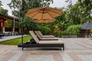 un grupo de tumbonas con sombrilla en Shanthi Kunnj Riverside Exotica Chikmagalur, en Chikmagalur