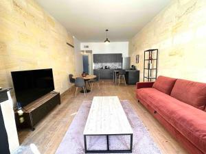 ein Wohnzimmer mit einem roten Sofa und einem Tisch in der Unterkunft Hypercentre - FREE Parking - clim - wifi - netflix in Libourne