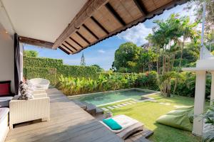 un patio trasero con piscina y terraza de madera en Villa Bumi en Kerobokan