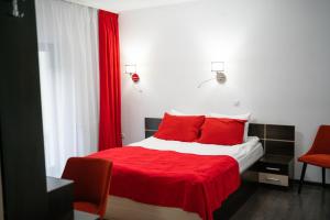 um quarto com uma cama com lençóis vermelhos e almofadas vermelhas em Piscul Negru Hotel - Transfagarasan em Cumpăna