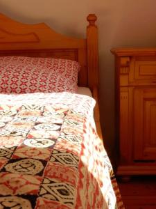 a bed with a quilt and a dresser in a bedroom at Ländliches Wohnen zwischen Erfurt und Gotha in Erfurt