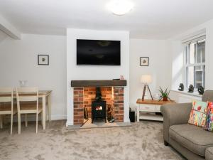 a living room with a fireplace with a tv on the wall at Ramblers Rest in Sedbergh