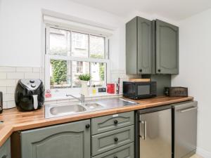 a kitchen with green cabinets and a sink at Ramblers Rest in Sedbergh
