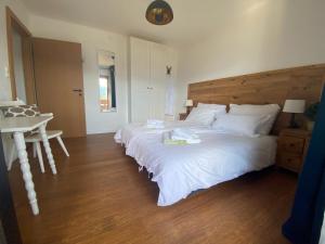 a bedroom with a large white bed and a table at Haus Otis in Millstatt