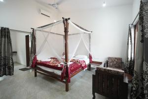 ein Schlafzimmer mit einem Himmelbett und einem Stuhl in der Unterkunft Maior Roma by Jolly Jolly Lester in Vagator