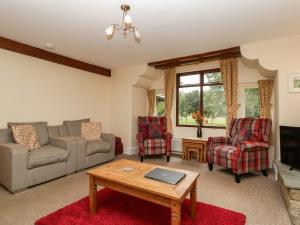 a living room with a couch and chairs and a table at Keepers Cottage in Leominster