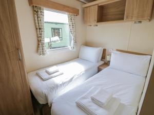 2 camas en una habitación pequeña con ventana en Heron en Leominster