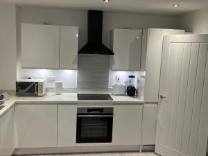 a kitchen with white cabinets and a stove top oven at Luxe City Centre in Birmingham