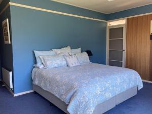 a bedroom with a large bed with blue walls at Balclutha in Point Lonsdale