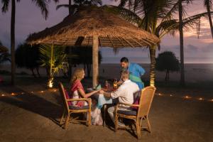 een groep mensen die aan een tafel zitten onder een paraplu bij Neeleshwar Hermitage in Nīleshwar