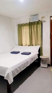 a bedroom with a bed with white sheets and a window at Rain Haven Lodging House in Coron