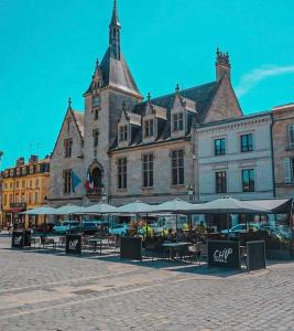 a large building with tables and umbrellas in front of it at 5- Hypercentre - 4pers - clim - terrasse - Netflix in Libourne