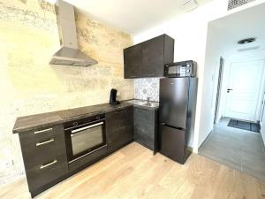 a kitchen with black cabinets and a refrigerator at Hypercentre - 4pers - clim - terrasse - Netflix in Libourne