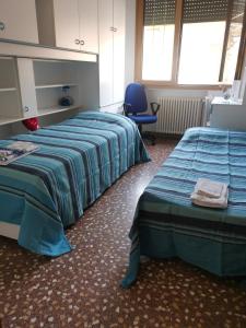 Habitación con 2 camas y silla azul en CASA CATERINA en Romano D'Ezzelino