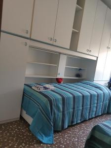 Cama en habitación con armarios blancos en CASA CATERINA, en Romano D'Ezzelino