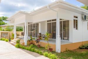 a white house with glass doors and a patio at Macmillan's Holiday Villas in Grand'Anse Praslin