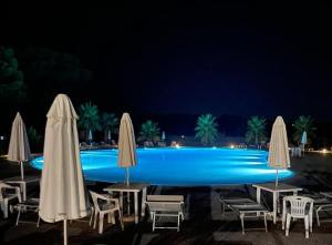 una piscina con sedie e ombrelloni di notte di Interno H10 - Olimpia Residence a Policoro