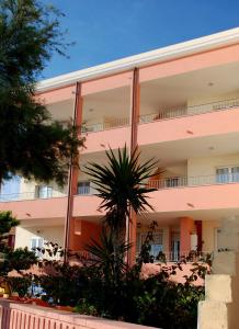 un edificio rosa con una palmera delante en Guest House Sea Rooms Alghero, en Alghero