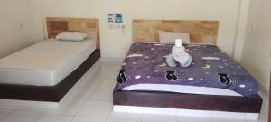 un dormitorio con una cama con un animal de peluche en Amed Stop Inn Homestay, Rooftop Restaurant and Bar en Amed