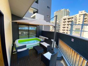 福岡的住宿－NK Hotels，一个带遮阳伞和游泳池的阳台