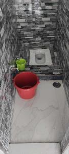 a bathroom with a red bucket and a toilet at OYO S K Hotel in Morādābād