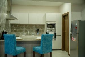 a kitchen with two blue chairs at a counter at Skynest Residences Entire Furnished Apartment, Westlands in Nairobi