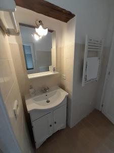a white bathroom with a sink and a mirror at La Casetta di Treville in Ozzano Monferrato