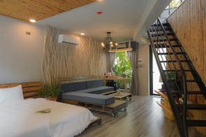 ein Schlafzimmer mit einem Bett und einer Treppe und einem Sofa in der Unterkunft Babylon Mini Resort in Vũng Tàu