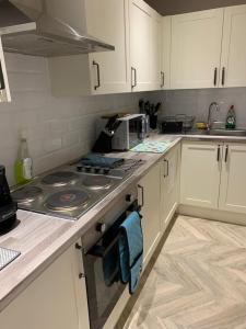 a kitchen with white cabinets and a stove top oven at Cambridge Suites in Harmondsworth