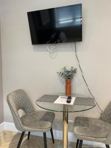 a table with two chairs and a television on a wall at Cambridge Suites in Harmondsworth