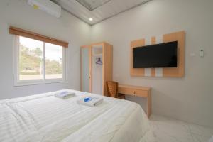 a bedroom with a bed and a tv on a wall at Lombokhouse Mandalika in Kuta Lombok