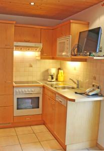 a kitchen with wooden cabinets and a sink and a microwave at Appartements Drei Wannen in Damuls