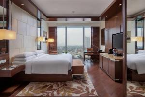 a bedroom with two beds and a desk and a television at JW Marriott Hotel Hanoi in Hanoi