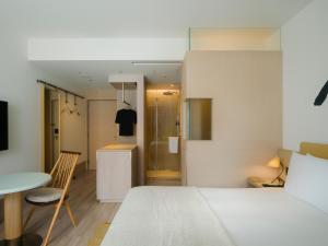a bedroom with a bed and a table and a kitchen at Zentis Osaka in Osaka