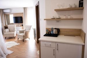 a kitchen with white cabinets and a living room at Marino Lux Prenoćište in Požarevac