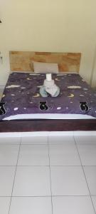 a bed with a purple comforter on top of it at Amed Stop Inn Homestay, Rooftop Restaurant and Bar in Amed