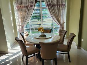 una sala da pranzo con tavolo, sedie e finestra di Wakaf Bharu Garden Stay Semi-D By UJ a Kota Bharu