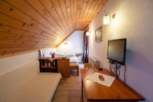 a room with a bed and a tv and a table at Sobe Odar Andrej in Bohinj