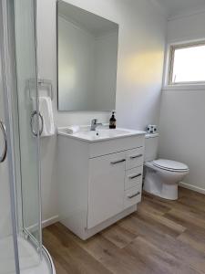 Baño blanco con lavabo y aseo en Caves Motor Inn en Te Kuiti