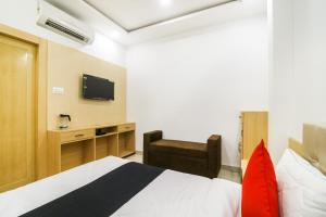 um quarto com uma cama, uma cadeira e uma televisão em Capital O 61009 Hotel Raj Mahal Sarnath em Varanasi