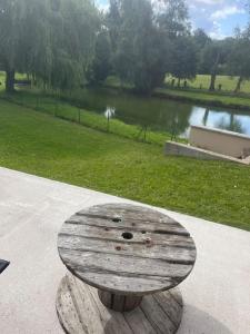 un banco de madera sentado junto a un parque con un lago en La petite maison, en Plélan-le-Petit