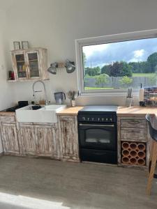cocina con fogones, fregadero y ventana en La petite maison, en Plélan-le-Petit